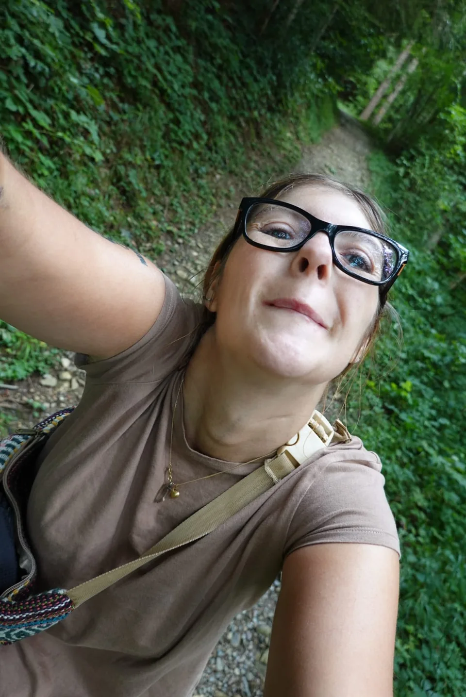 Porträt von Nadia mit Brille auf einem Weg im Grünen.
